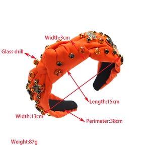 Detail view of orange Halloween headband with spider web pendant and glass rhinestones
