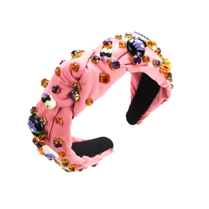Dettaglio del cerchietto per Halloween in raso rosa con strass e decori di teschi