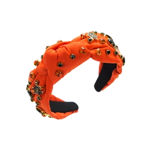 Detail of orange satin Halloween headband with rhinestones and golden spider web charm