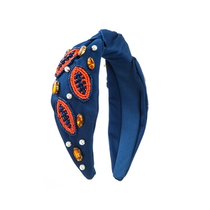 Détail de perles de rugby et strass orange sur un bandeau large à nœud bleu marine