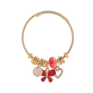 Dettaglio del bracciale dorato a treccia con ciondolo a farfalla rossa e cuore