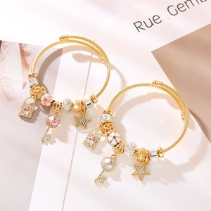 Bracciale regolabile in oro e acciaio con ciondoli a stella, chiave e cuore con cristalli