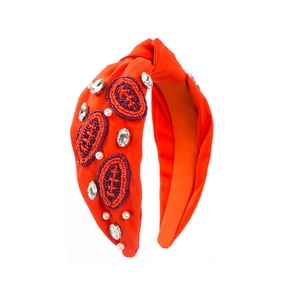 Détail d'un serre-tête noué orange avec patchs de rugby perlés et de strass