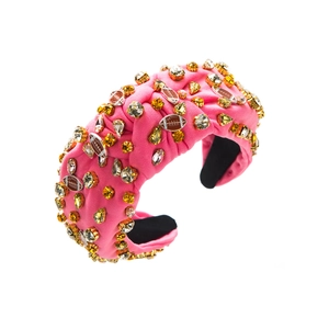 Détail d'un serre-tête rembourré rose avec cristaux étincelants et pendentifs rugby