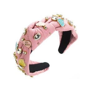 Détail d'un serre-tête rose noué orné de strass et de breloques en forme de cœur sucrés