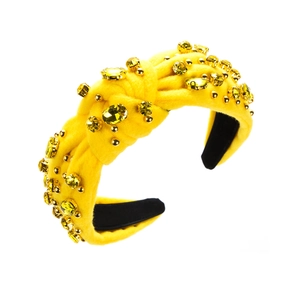Detail eines gelben Samtstirnbands mit Goldnieten und funkelnden gelben Kristallen