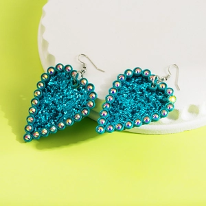 Sparkly blue heart earrings with glitter and rhinestones on a stylish white platform