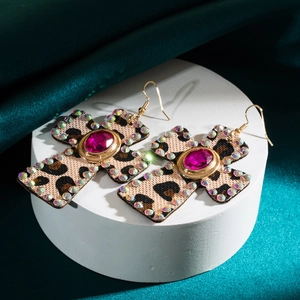 Vintage leopard print cross earrings with purple gem and rhinestone halo on stone