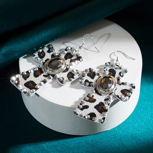 Macro view of leopard print cross earrings with sparkling rhinestones and grey gemstone