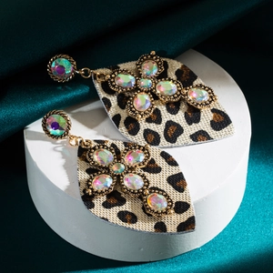 Vue détaillée de boucles d'oreilles léopard avec pierres turquoise et design de croix dorée