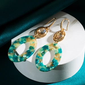 Detail view of retro geometric oval acrylic drop earrings with marble pattern and gold metal