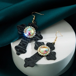 Detail van vintage leren kruis oorbellen met kleurrijke edelsteen en kristalaccenten