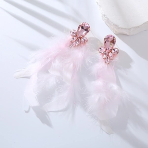Dettaglio di orecchini di piume rosa con fiore di cristallo su pietra bianca pura
