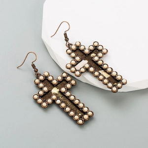 Détail macro de boucles d'oreilles croix avec cadre en bronze et perles turquoise