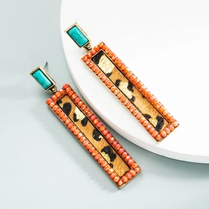Macro detail of retro geometric earrings with leopard print fabric and turquoise stone