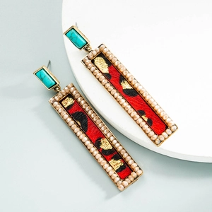 Macro shot of rectangular earrings featuring red leopard print and golden bead trim