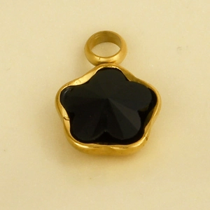Detailansicht eines schwarzen Edelsteinanhängers mit goldenem Rand in Blumenform