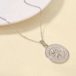 Detailed macro of silver compass pendant necklace with engraved cardinal directions