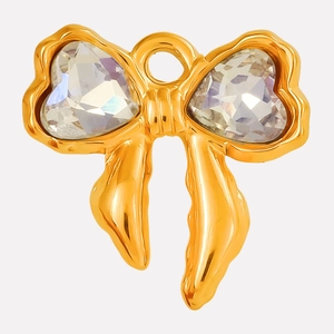 Detailed close-up of bow-shaped gold pendant featuring heart-shaped crystal inlay