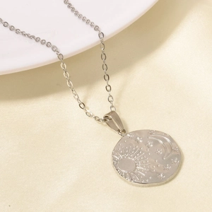 Detailed macro shot of sun, moon and star relief on silver 304 stainless steel pendant