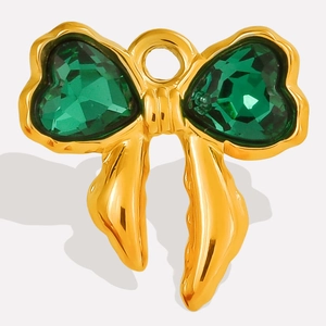 Macro view of golden bow pendant with two green heart-shaped faceted gemstones
