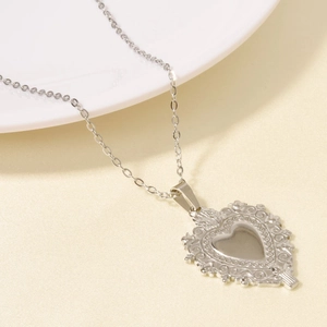 Dettaglio del ciondolo a cuore argento con rilievo barocco su una sottile catena a maglie