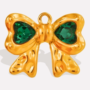 Macro detail van gouden strikhanger met smaragdgroene hartkristallen en gehamerd metaal