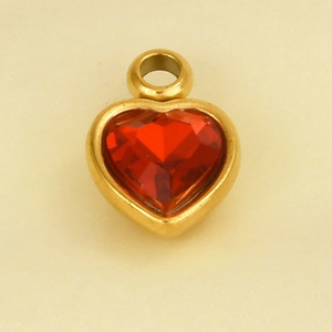 Macro detail of heart-shaped gold pendant with faceted red crystal inlay and hook