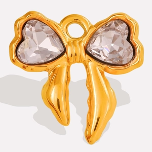 Macro view of a gold bow pendant featuring heart-shaped crystals and a polished metal finish