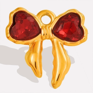 Macro detail of gold-plated bow charm with two red heart-shaped crystals for jewelry DIY