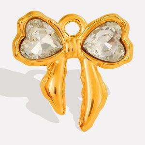 Close-up of golden bow pendant with sparkling heart-shaped glass crystals for DIY jewelry