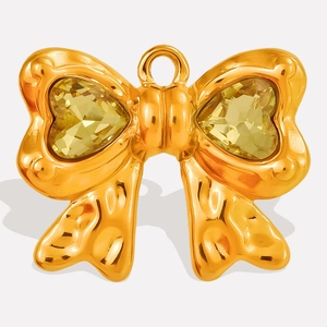 Detail macro-opname van de strikvormige hanger met gehamerd goud en gele hartvormige stenen