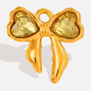 Macro detail of gold bow pendant with faceted yellow heart-shaped crystal stone