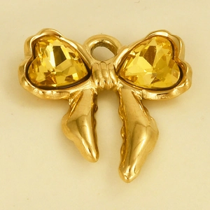 Macro shot of a golden bow-shaped pendant with heart-shaped yellow crystal stones