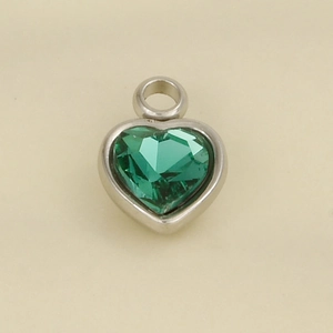 Macro detail of heart-shaped pendant with emerald green faceted glass and silver-tone frame