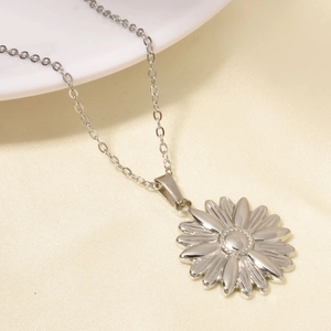 Gros plan d'un collier pendentif fleur argenté sur un élégant tissu en soie blanc