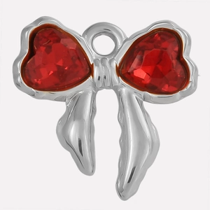 Close-up of a silver bow pendant with red heart-shaped crystals for jewelry making