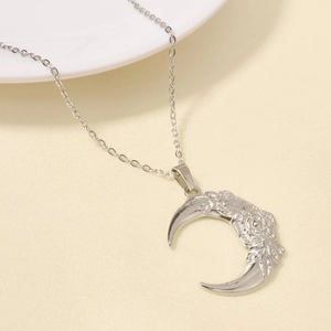 Macro shot of silver crescent moon necklace pendant featuring intricate rose engravings