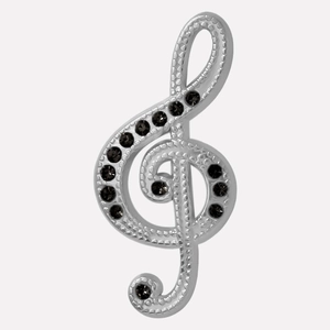 Détail macro du pendentif clé de sol en métal argenté texturé et strass noirs incrustés