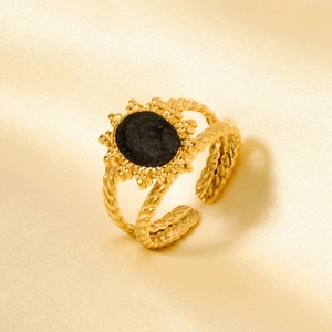 Détail de bague vintage dorée avec motif soleil et pierre noire sur anneau tressé