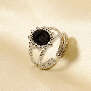 Détail d'une bague fleur en acier inoxydable avec motif soleil noir et anneau torsadé