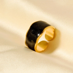 Detailed macro view of a gold-plated wavy ring with black enamel on champagne silk