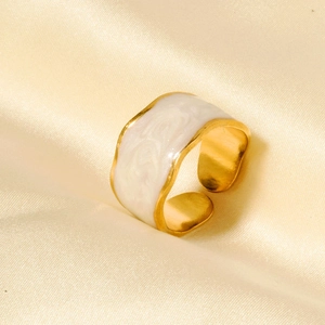 Detail of wide gold adjustable ring with white enamel inlay on beige silk fabric