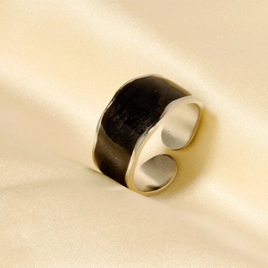 Detail shot of black enamel 304 stainless steel open ring on champagne satin fabric