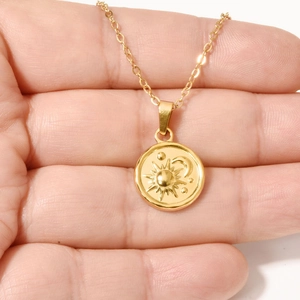 Handheld view of a minimalist 18k gold plated stainless steel sun moon and star pendant necklace