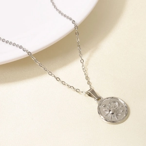 Close-up of a silver sun and moon medallion pendant on a delicate chain necklace