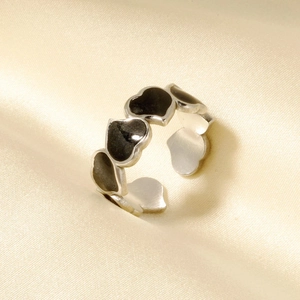 Detail of vintage 304 stainless steel open ring with black enamel heart patterns