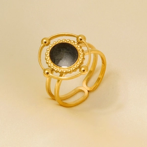 Detailed shot of gold-plated sun ring with black stone on a soft satin background