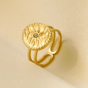 Detail of 18k gold plated sunburst ring with zircon stone on silk fabric background