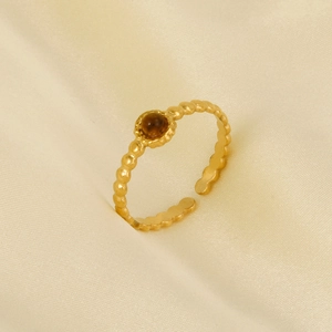 Detailed view of gold beaded open ring with round brown stone on satin background